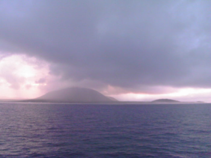 Ocean, cloudy skies, and an island in the distance in Galapagos Islands. Photo credit: L. Tripoli.