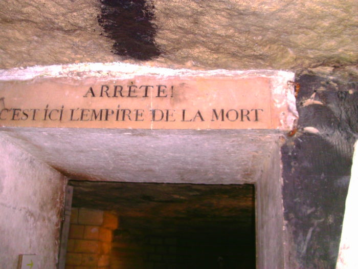 A sign in the Paris Catacombs translates to "Stop! This is the empire of the dead." Photo credit: L. Tripoli.