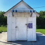 An image of the smallest post office in the United States, which is the Ochopee Post Office on Old U.S. Route 41 (the Tamiamia Trail) between Naples and Miami in Florida. The image depicts a small white building about the size of a lawnmower shed.Photo credit: M. Ciavardini.
