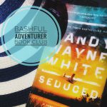 A sticker with the words "Bashful Adventurer Book Club" superimposed over a copy of the Randy Wayne White book, Seduced, atop a striped beach hat and beneath a pair of sunglasses.