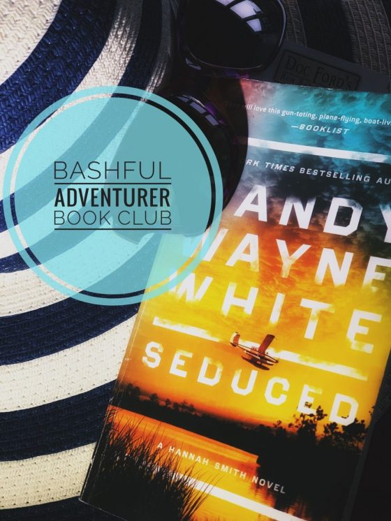 A sticker with the words "Bashful Adventurer Book Club" superimposed over a copy of the Randy Wayne White book, Seduced, atop a striped beach hat and beneath a pair of sunglasses.
