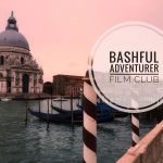 Am image of a canal in Venice, Italy featuring a church and gondolas and the words "Bashful Adventurer Film Club" superimposed. Photo credit: M. Ciavardini.
