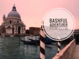 Am image of a canal in Venice, Italy featuring a church and gondolas and the words "Bashful Adventurer Film Club" superimposed. Photo credit: M. Ciavardini.